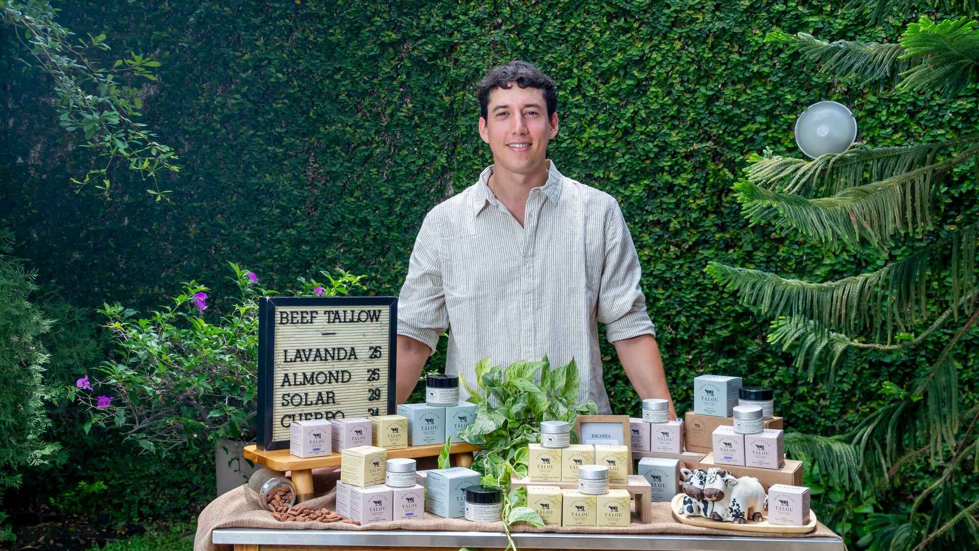 Fundador de Tálou junto a la mesa de producto, con la pizarra artesanal de la marca
